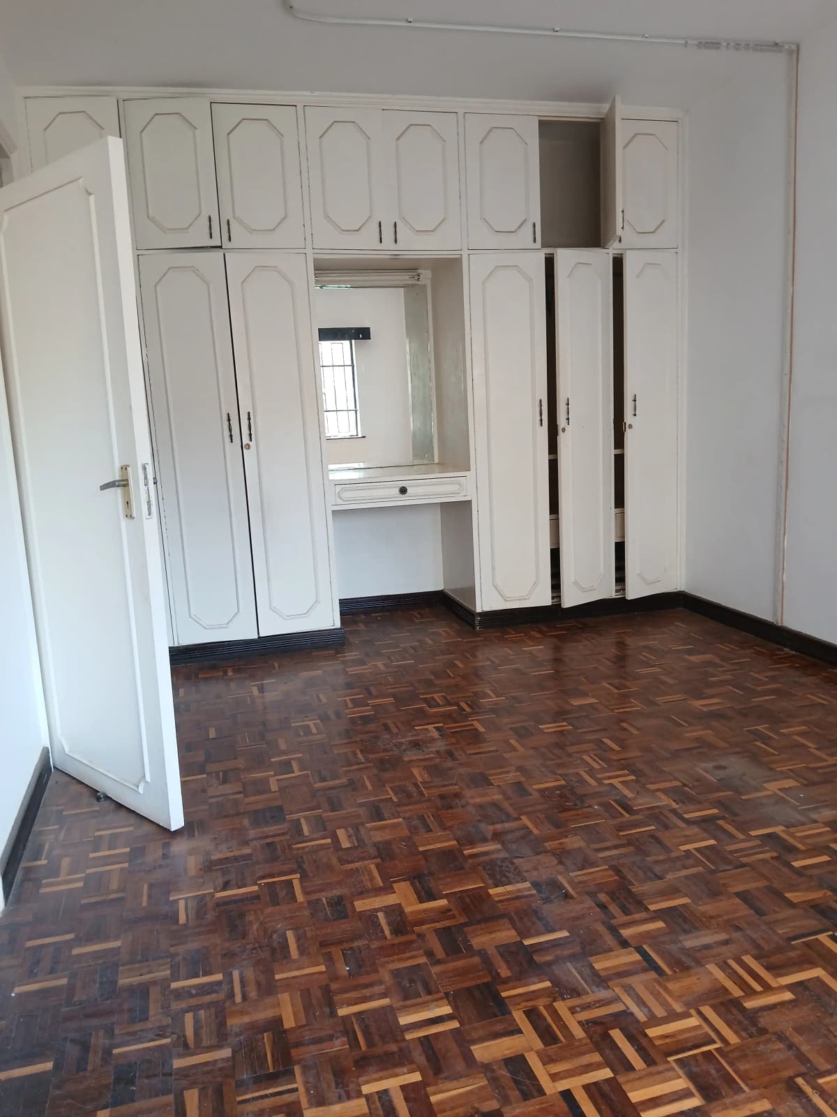 Spacious bedroom with built-in white wardrobes and parquet flooring