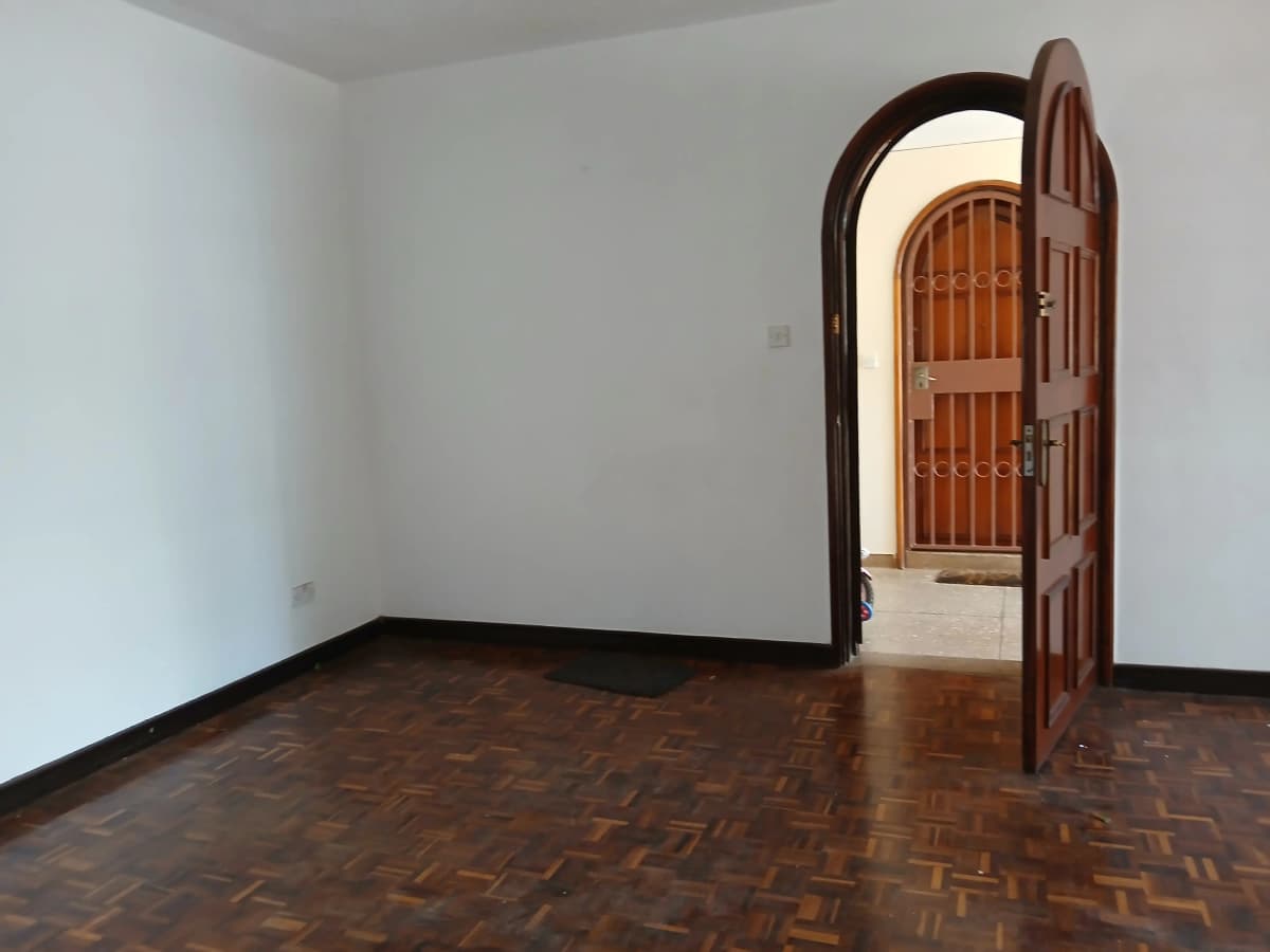 Empty bedroom with parquet flooring and arched wooden door