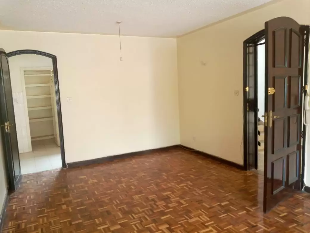 Spacious empty living room with parquet flooring and cream walls