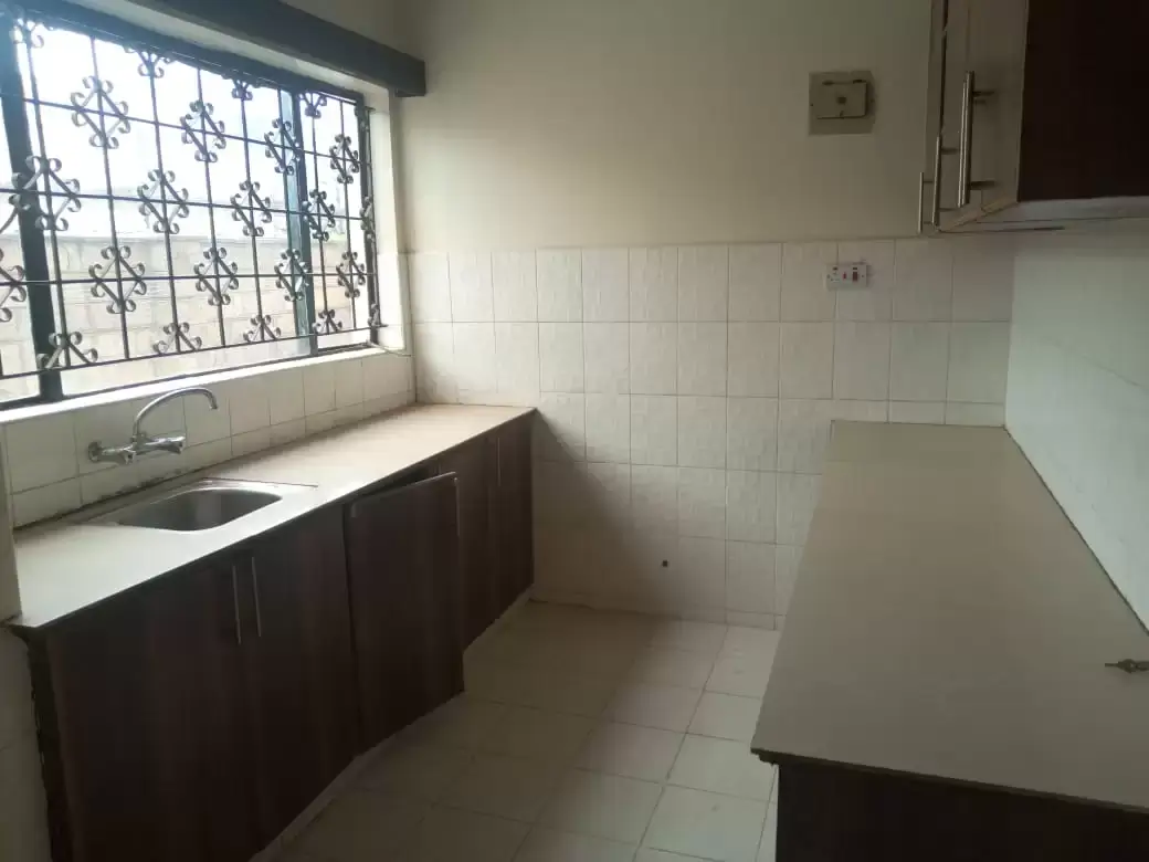 Compact kitchen with dark cabinetry and barred window