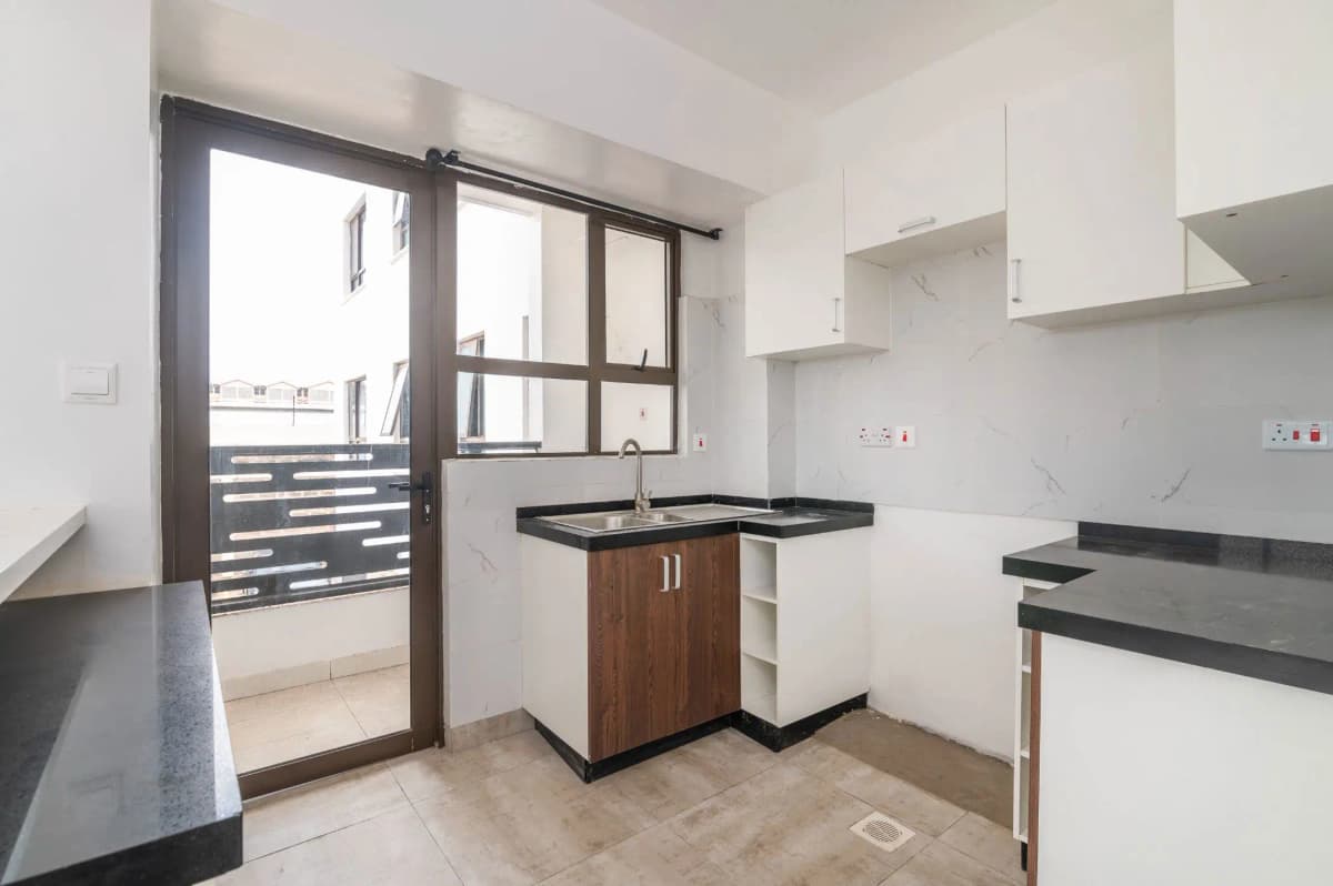 Modern kitchen with black countertops, island sink, sliding balcony door