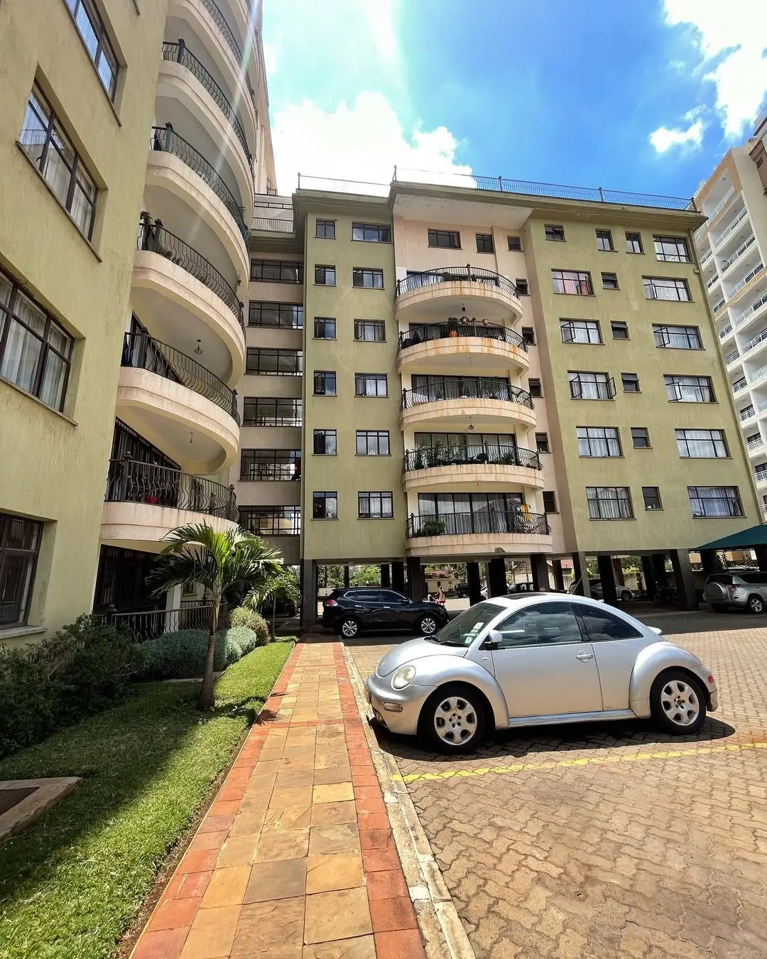 Multi-story residential building with curved balconies and parking compound