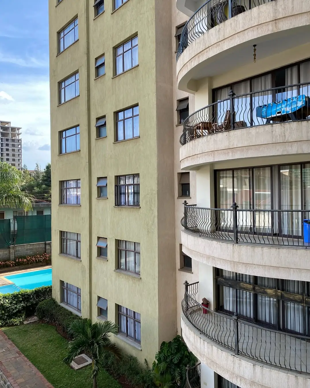 Multi-story residential building facade with curved balconies and pool
