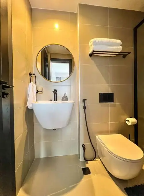 Modern bathroom with round mirror, wall-mounted sink, toilet