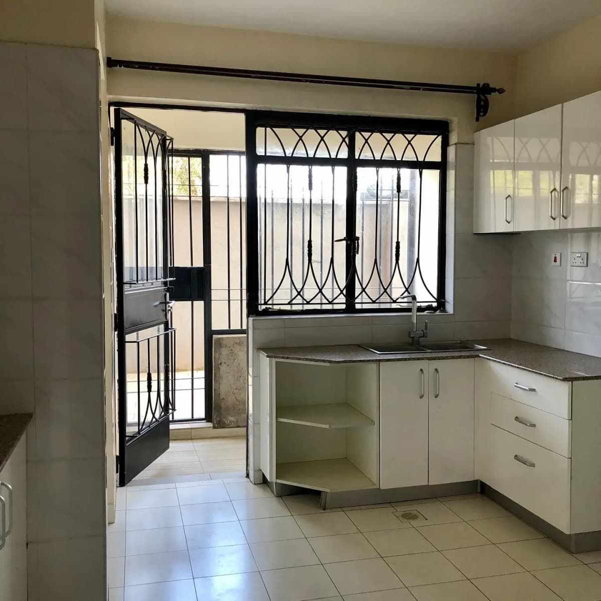 Compact kitchen with cream cabinetry and tiled flooring