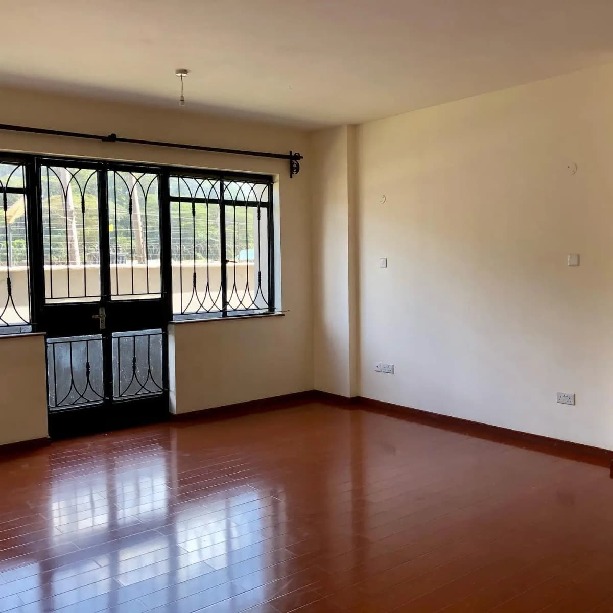 Spacious living room with polished wooden floors and balcony doors