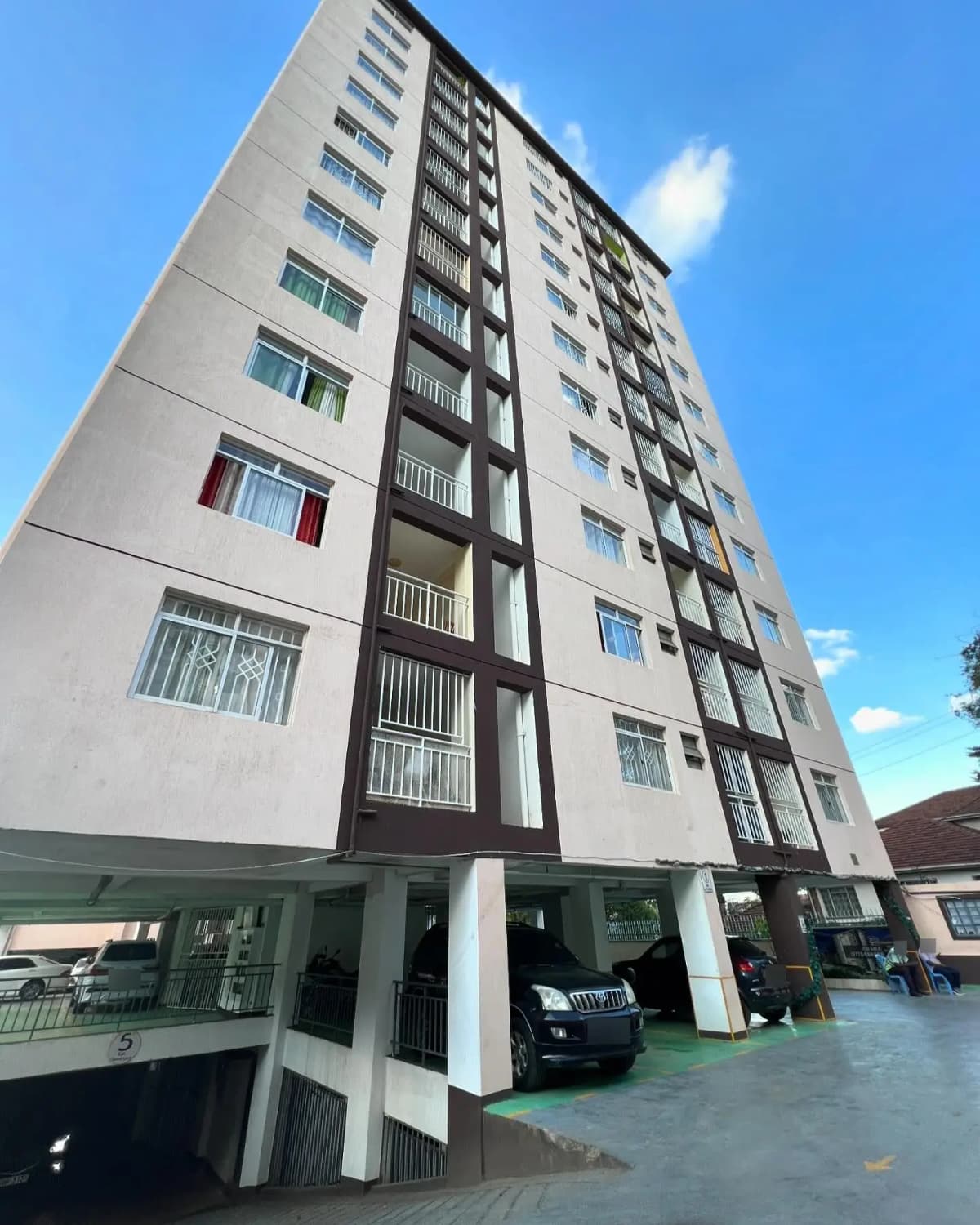 Modern multi-story apartment building facade with ground-level parking