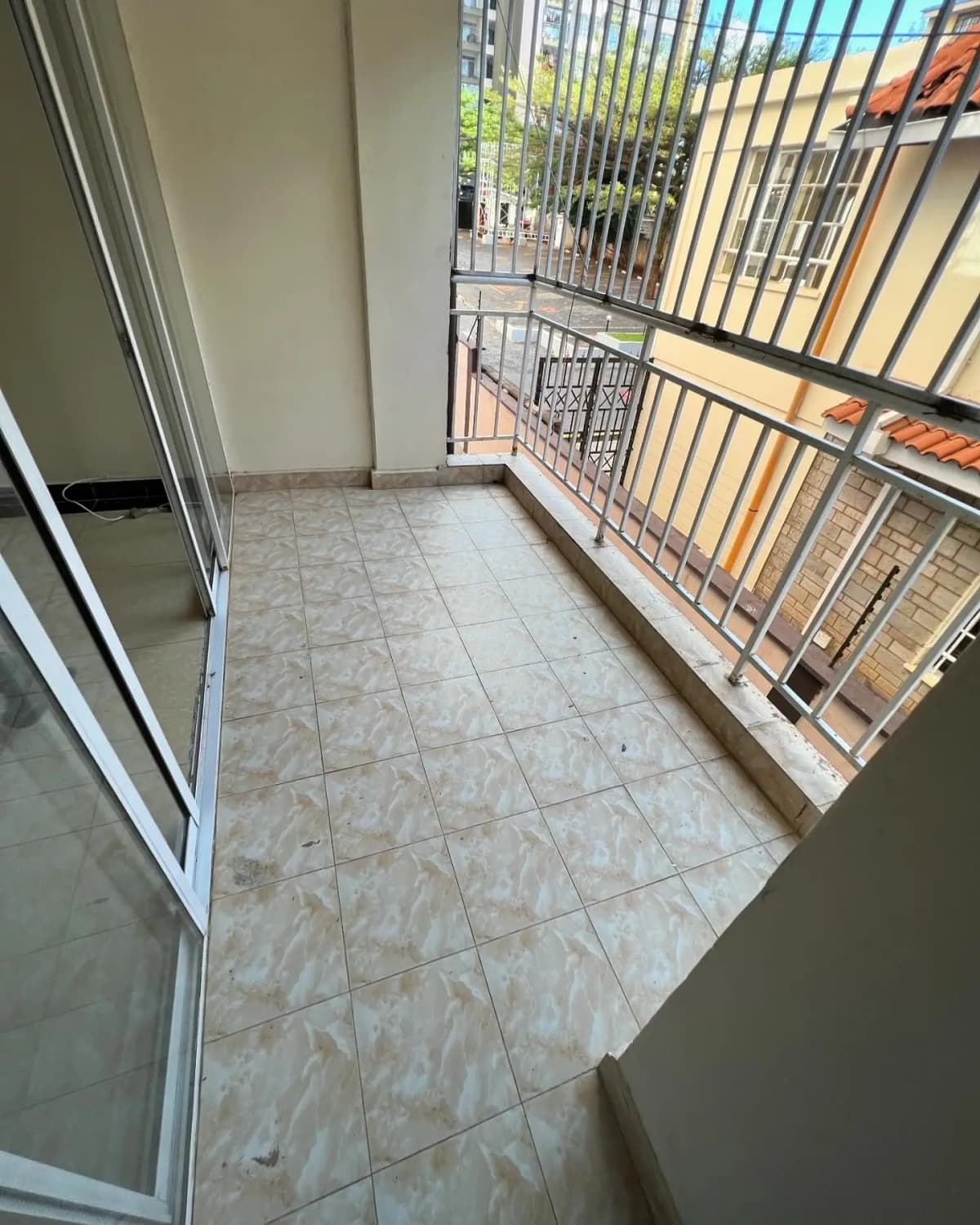 Tiled balcony with metal railing overlooking compound buildings