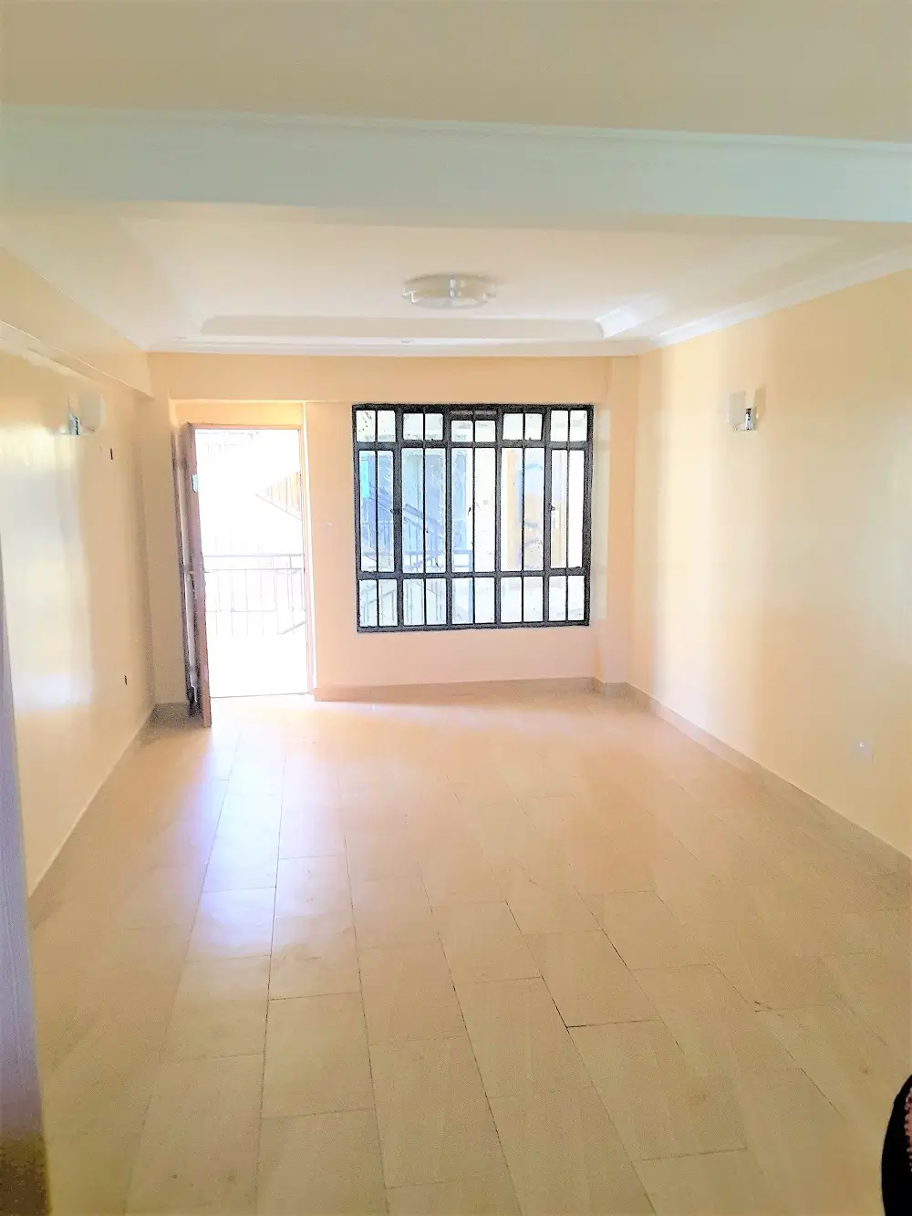 Spacious empty living room with barred window and cream tiles