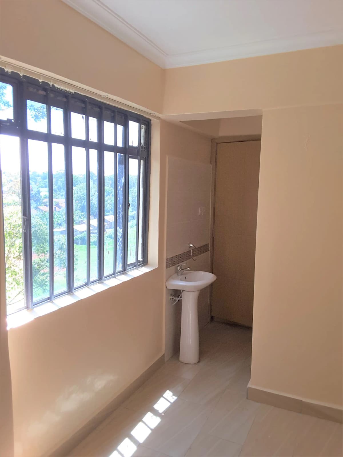 Compact bathroom with pedestal sink and barred window