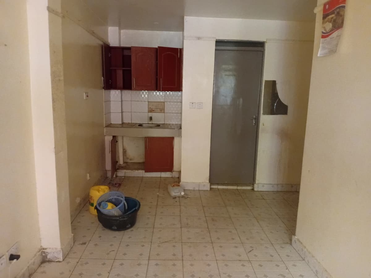 Compact kitchen with red cabinetry and tiled flooring
