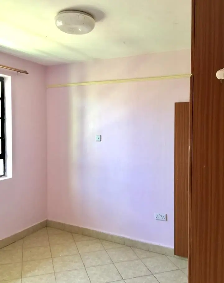 Empty bedroom with pink walls and tiled flooring