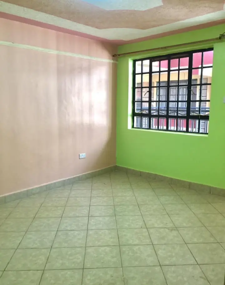 Empty bedroom with green accent wall and barred window