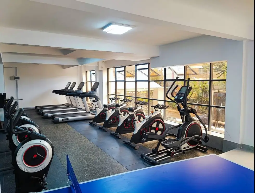 Modern gym with cardio equipment, exercise bikes, and large windows