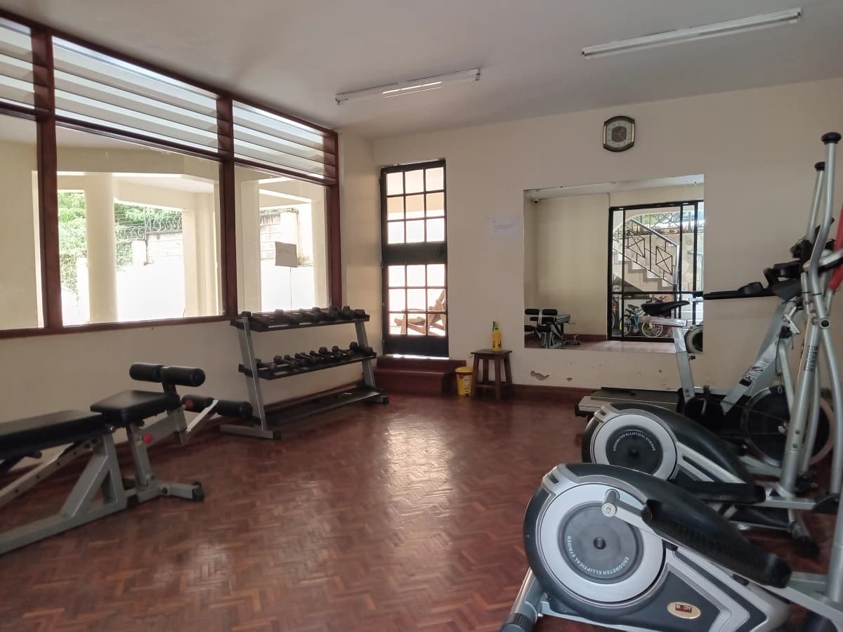 Spacious gym with cardio equipment, dumbbells, and mirrors