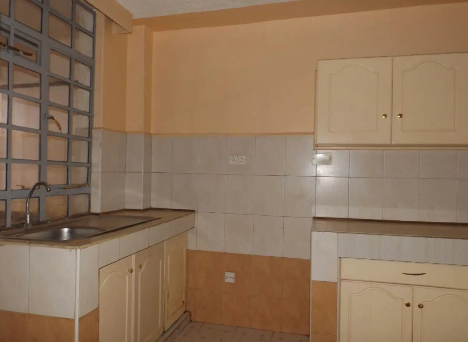 Compact kitchen with cream cabinets and white tile backsplash