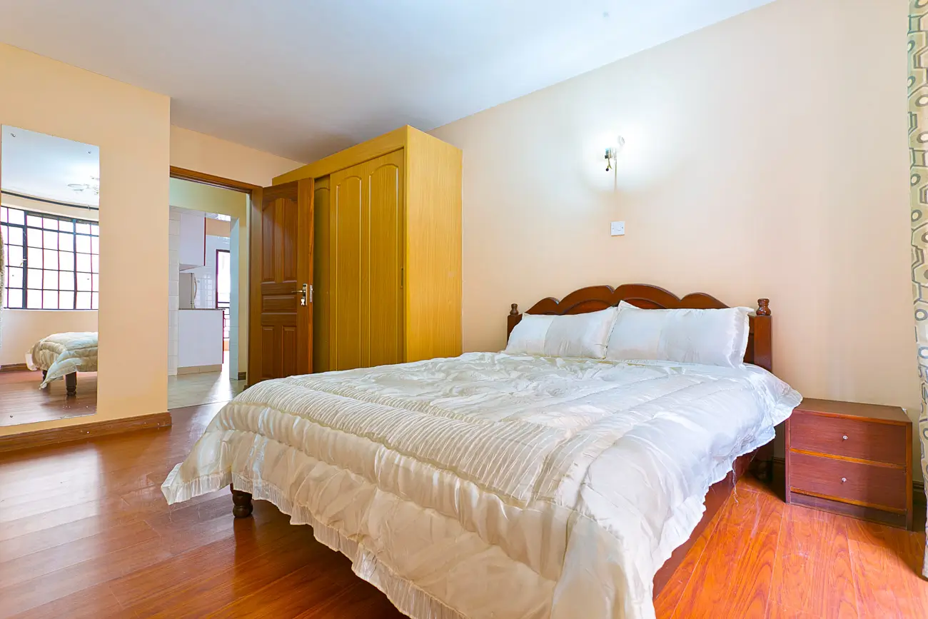 Master bedroom with wooden bed frame and en-suite bathroom visible