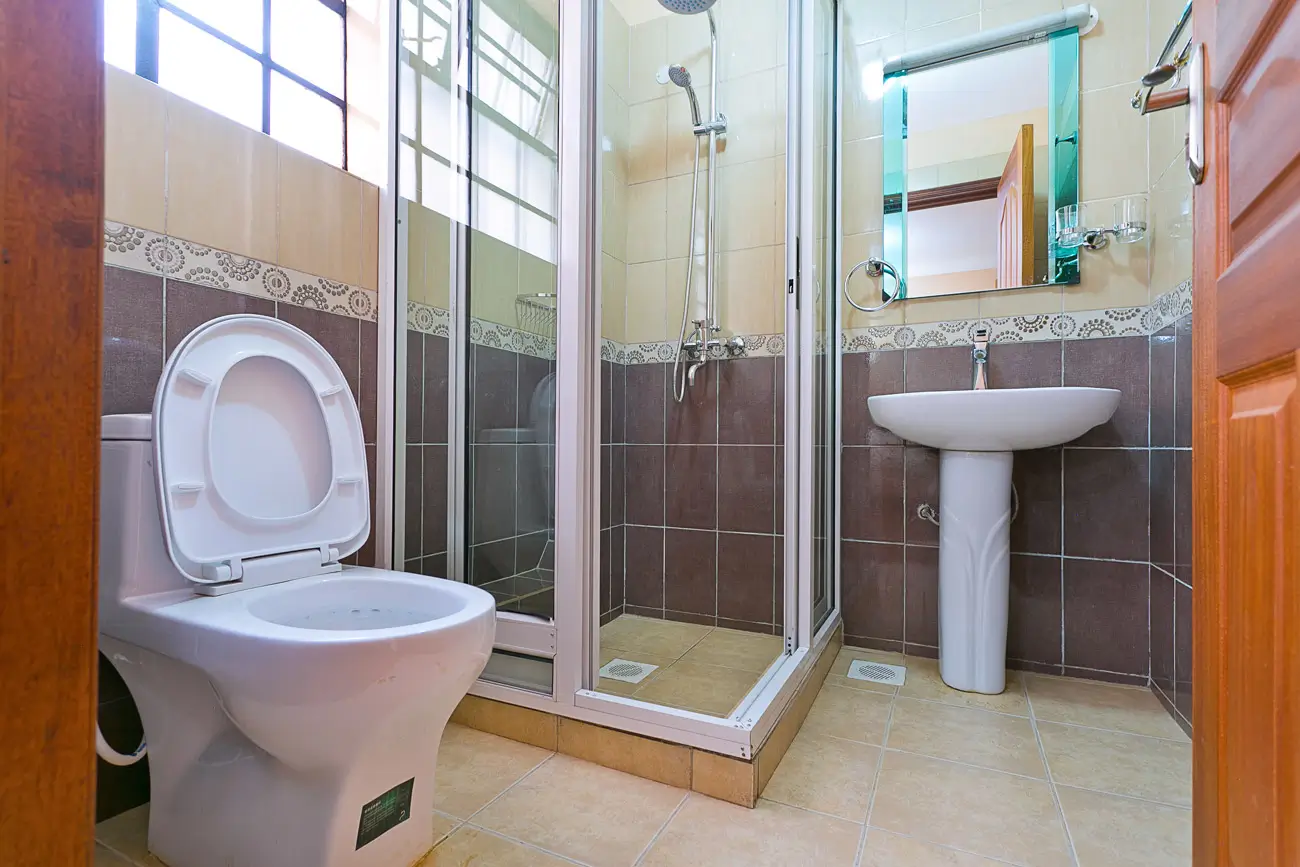 Spacious bathroom with toilet, pedestal sink, and shower enclosure