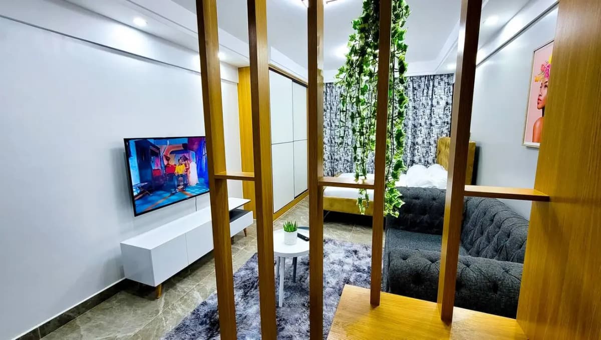 Modern open-plan living room with TV, wooden partitions, green accents