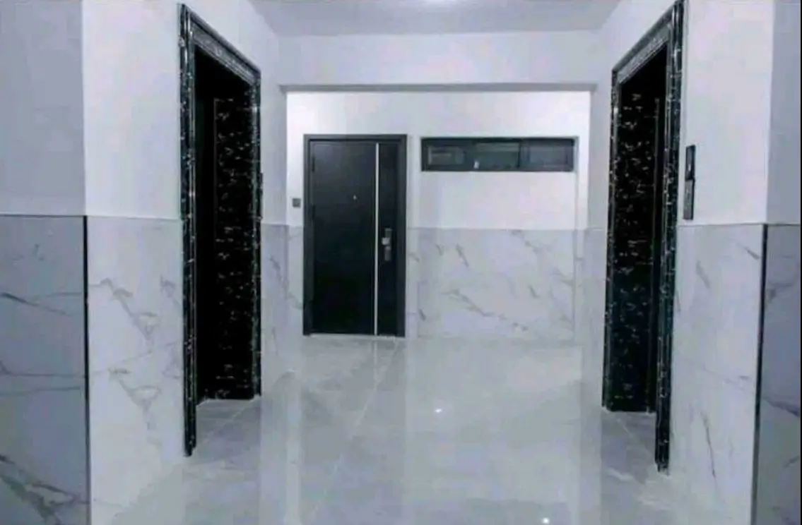 Modern lobby with marble walls, black doors, and polished flooring