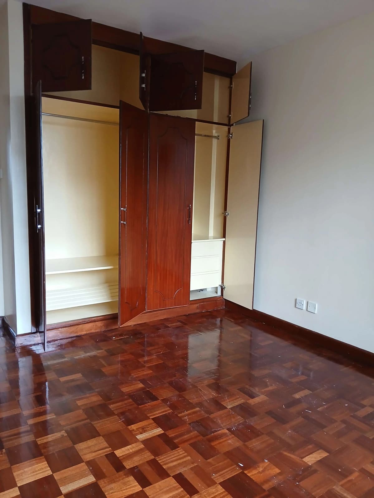Spacious bedroom with built-in wooden wardrobe and parquet flooring