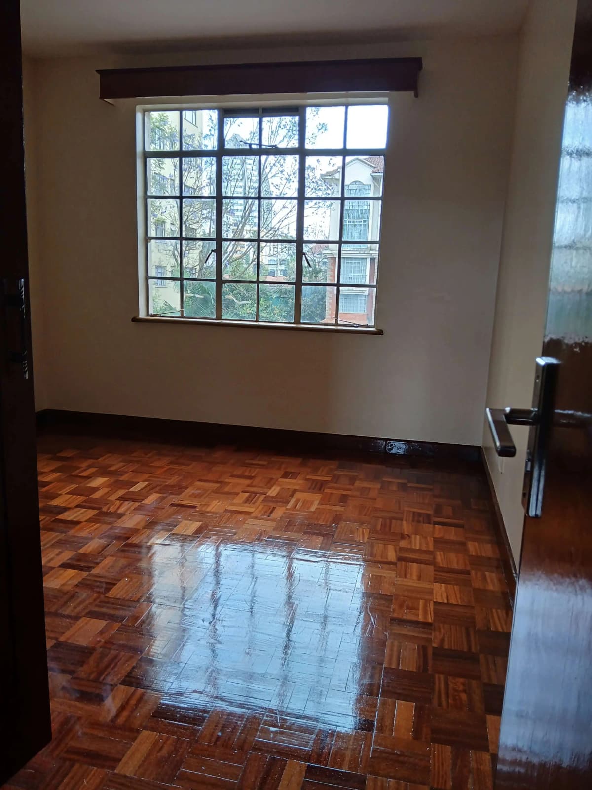 Spacious bedroom with large grid windows and wooden parquet flooring