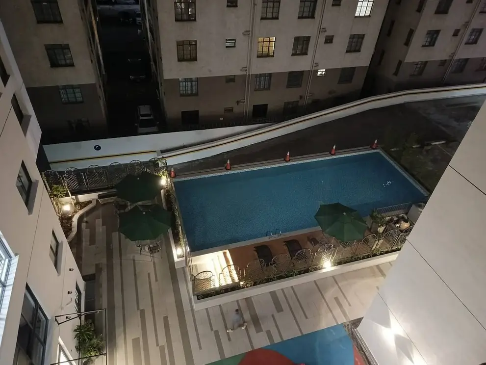 Rooftop swimming pool with evening lighting, surrounded by buildings