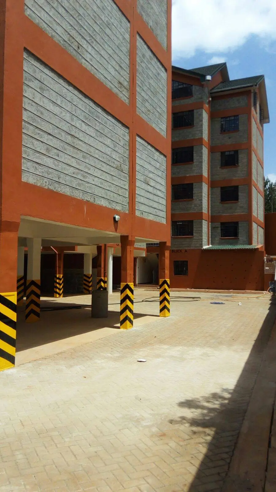 Underground parking bay with yellow safety bollards and building facade