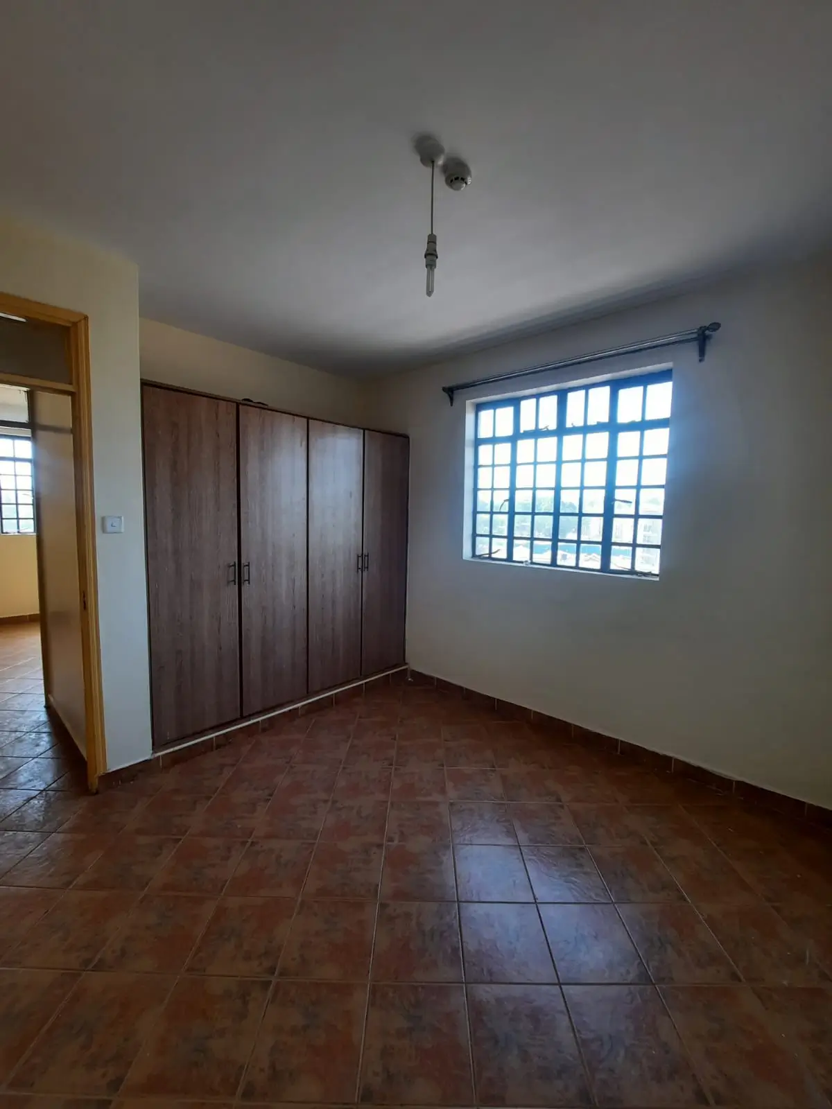 Spacious bedroom with wooden wardrobe and barred window