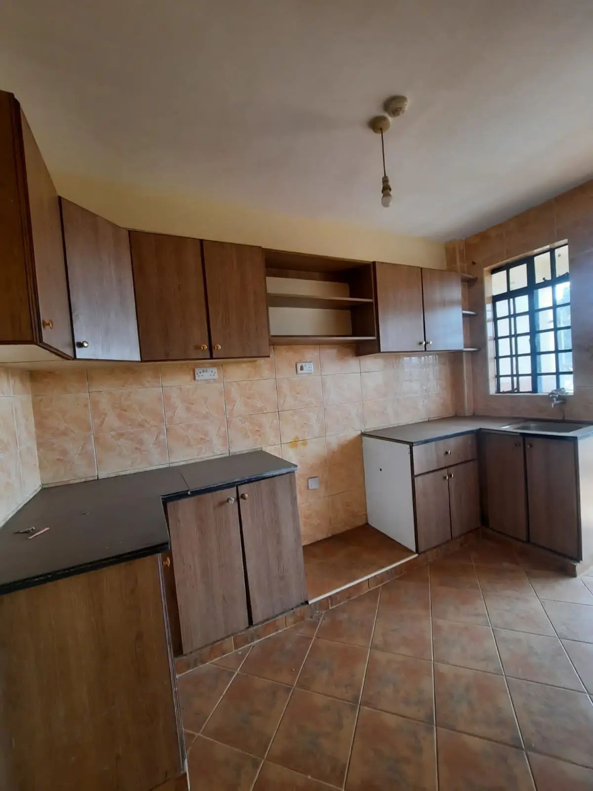 Spacious kitchen with wooden cabinets and terracotta tile flooring