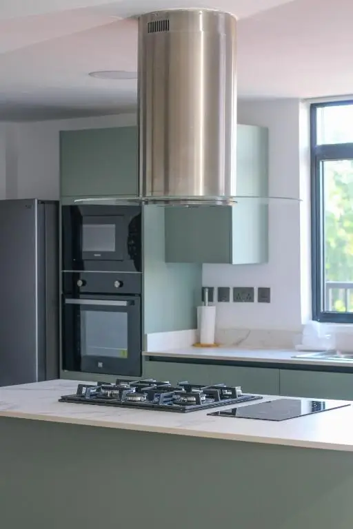 Modern kitchen with gas cooktop, stainless steel hood, built-in ovens