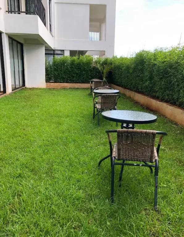 Well-manicured lawn with outdoor seating and hedge boundaries