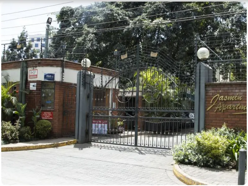 Secure gated apartment entrance with brick walls and landscaping