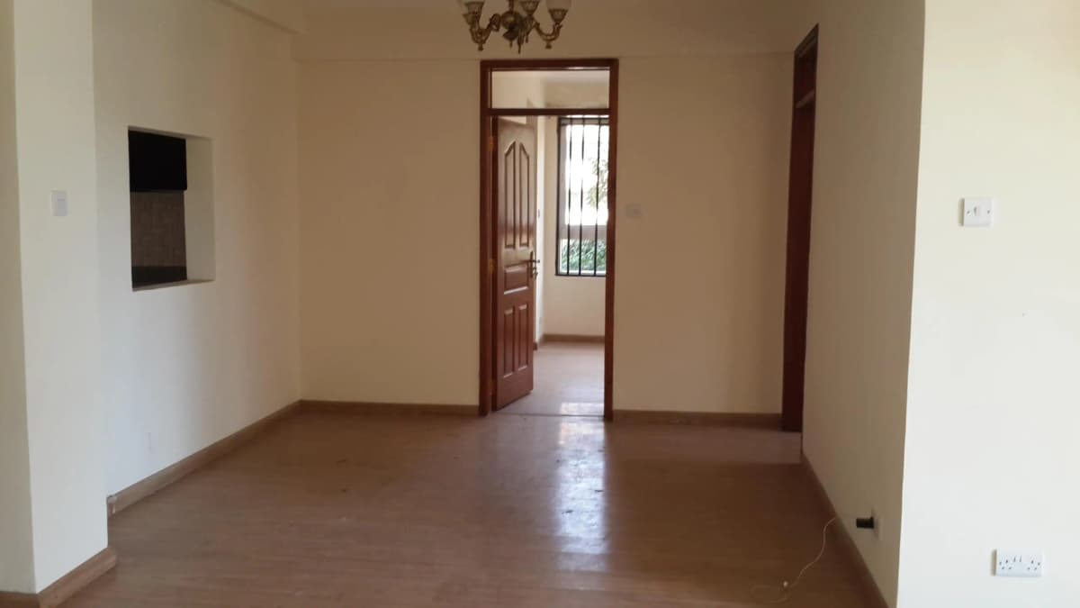 Empty living room with brown tile floor and wooden door