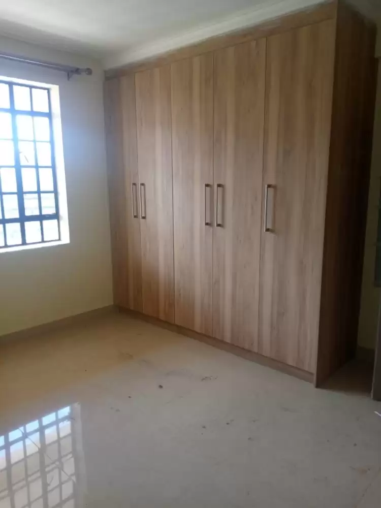 Empty bedroom with built-in wooden wardrobes and natural light