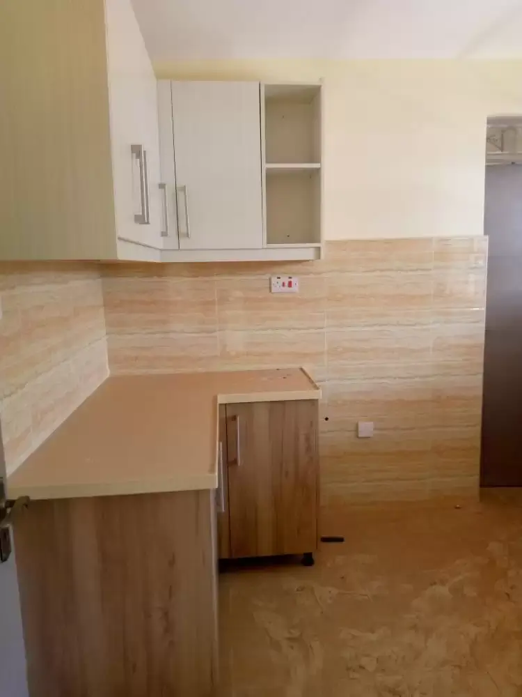 Compact kitchen with white cabinetry and wooden countertop