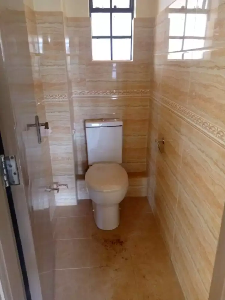 Compact bathroom with toilet, sink, and tiled walls