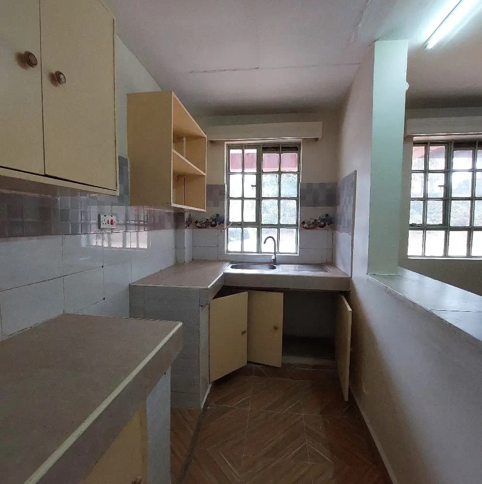 Compact galley kitchen with cream cabinets and tile backsplash