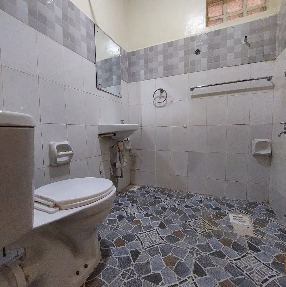 Compact bathroom with toilet, sink, and geometric floor tiles