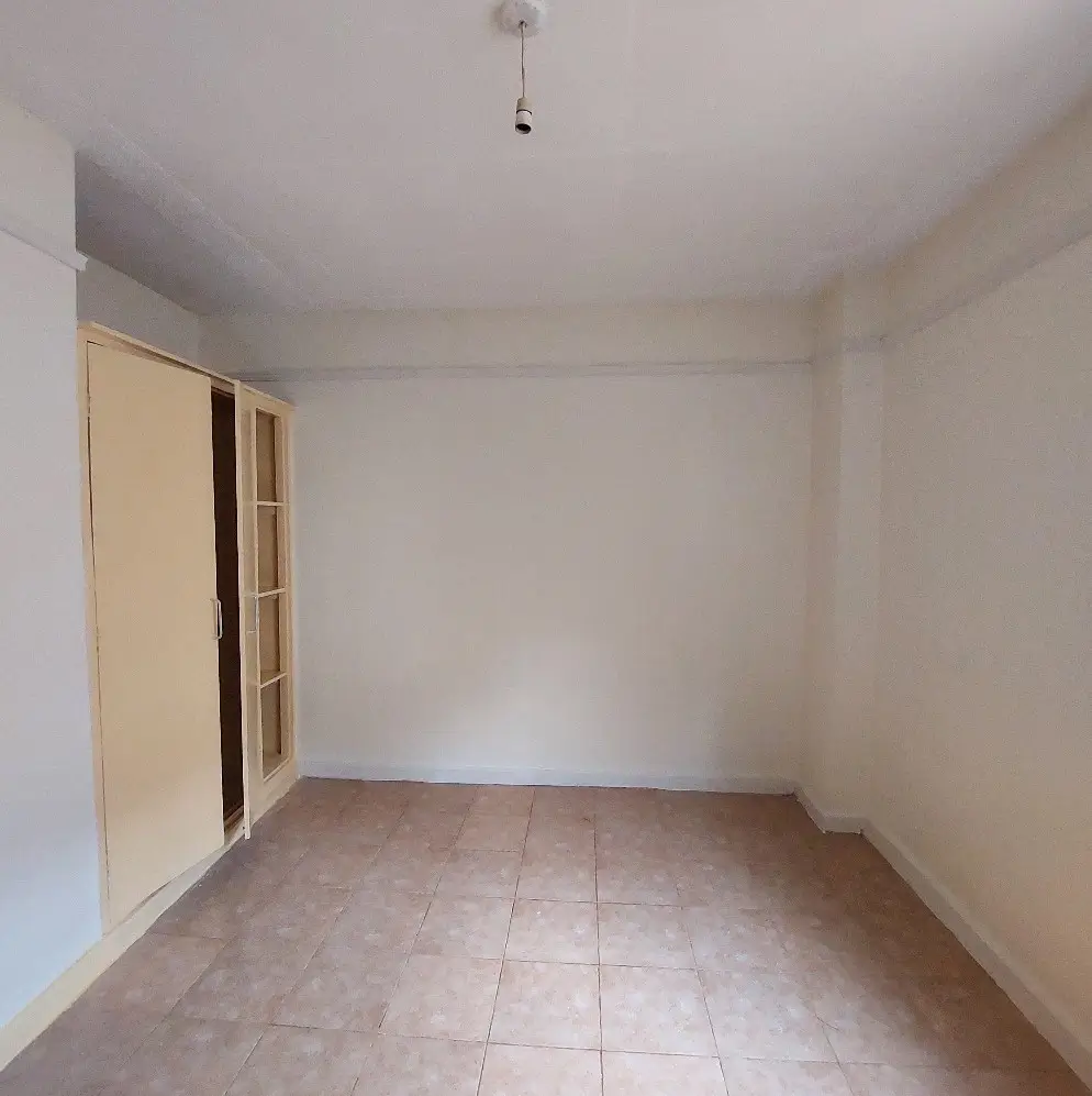Empty bedroom with tiled floor and built-in wardrobe