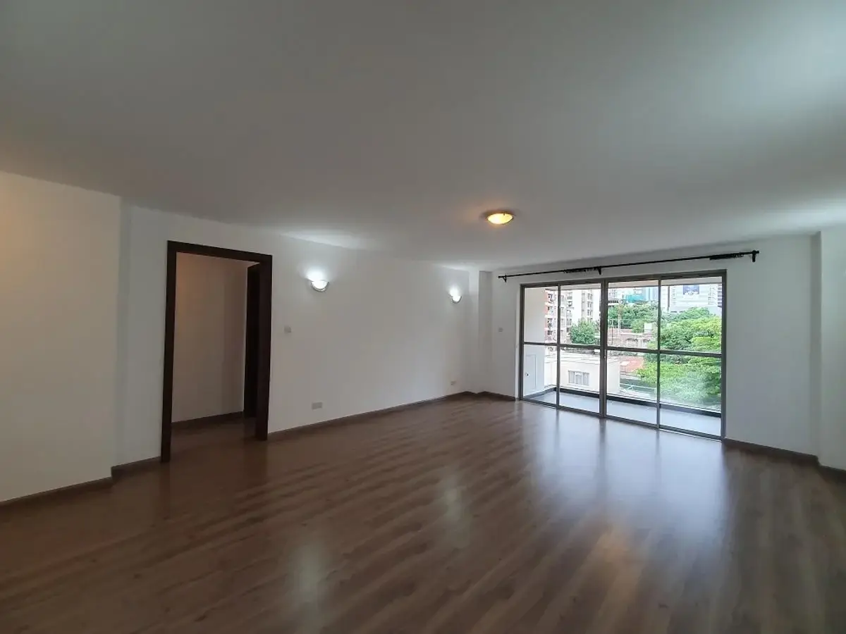 Spacious living room with dark wood flooring and natural light