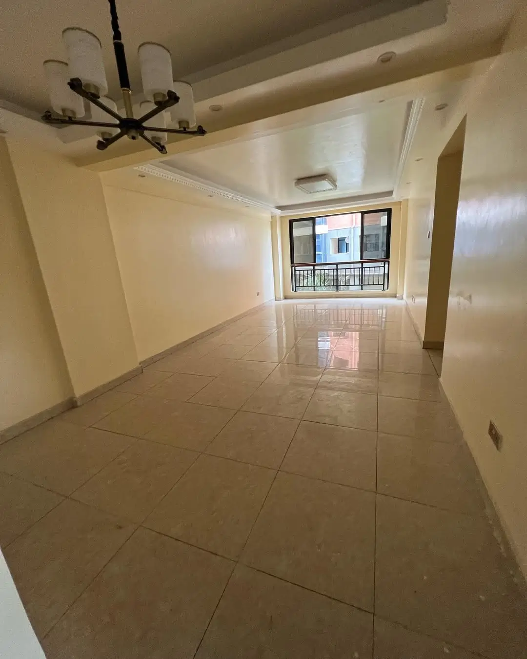 Empty living room with tiled flooring and modern chandelier