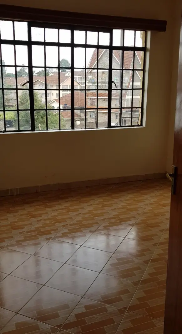Spacious living room with large barred window and mixed flooring