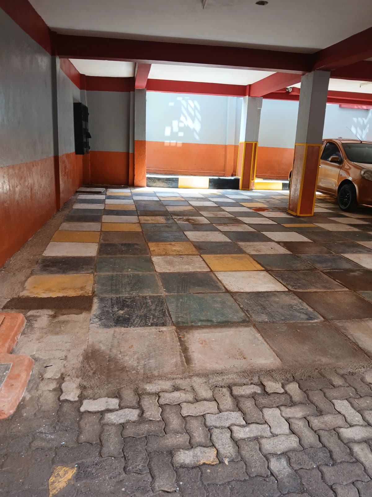 Covered parking bay with colorful tile flooring and support columns
