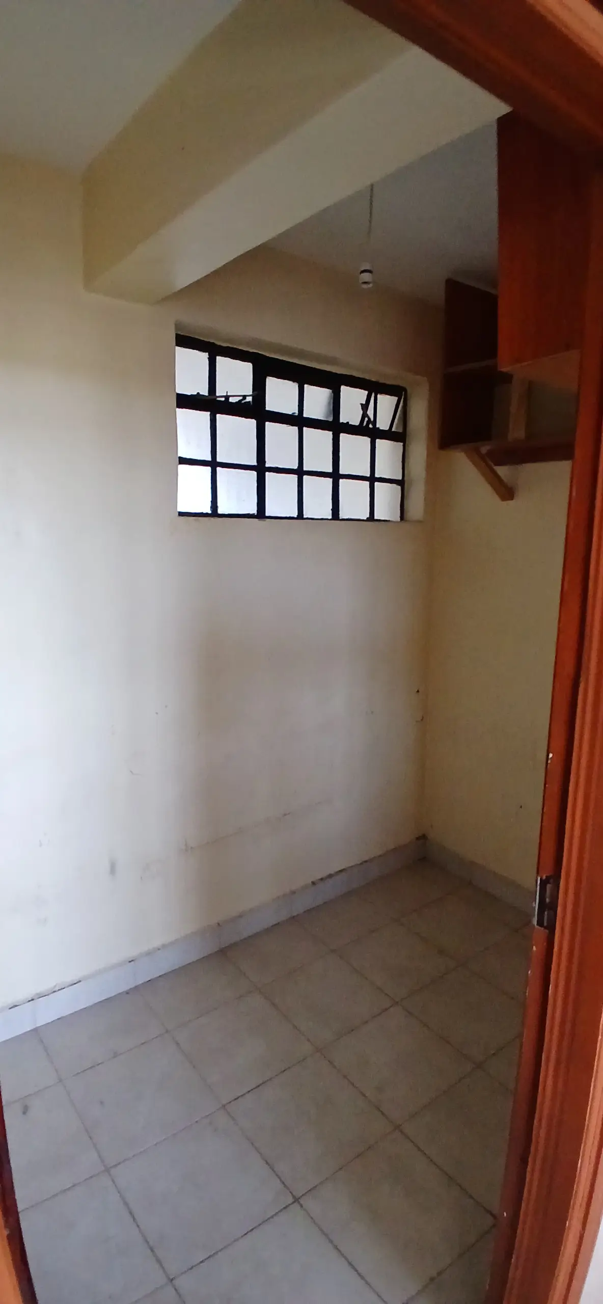 Bare bedroom with high window and wooden beam