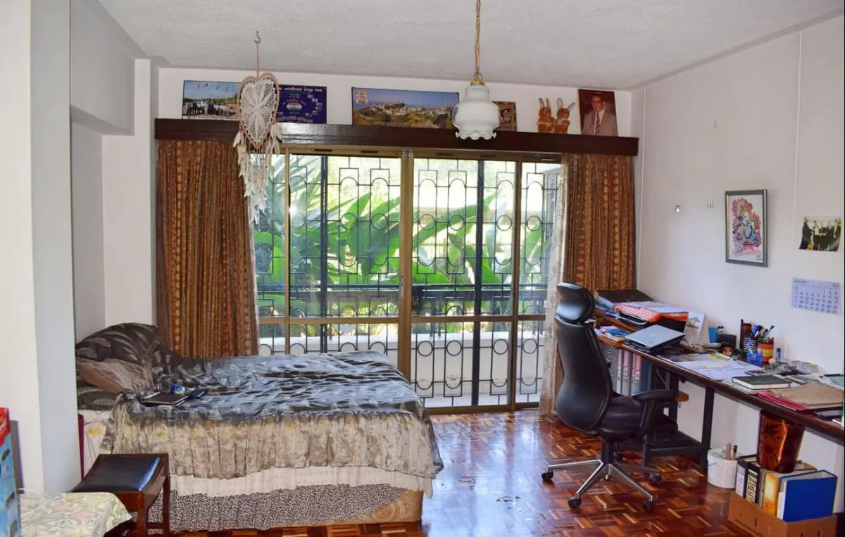 Spacious bedroom with large windows, work desk, and garden views