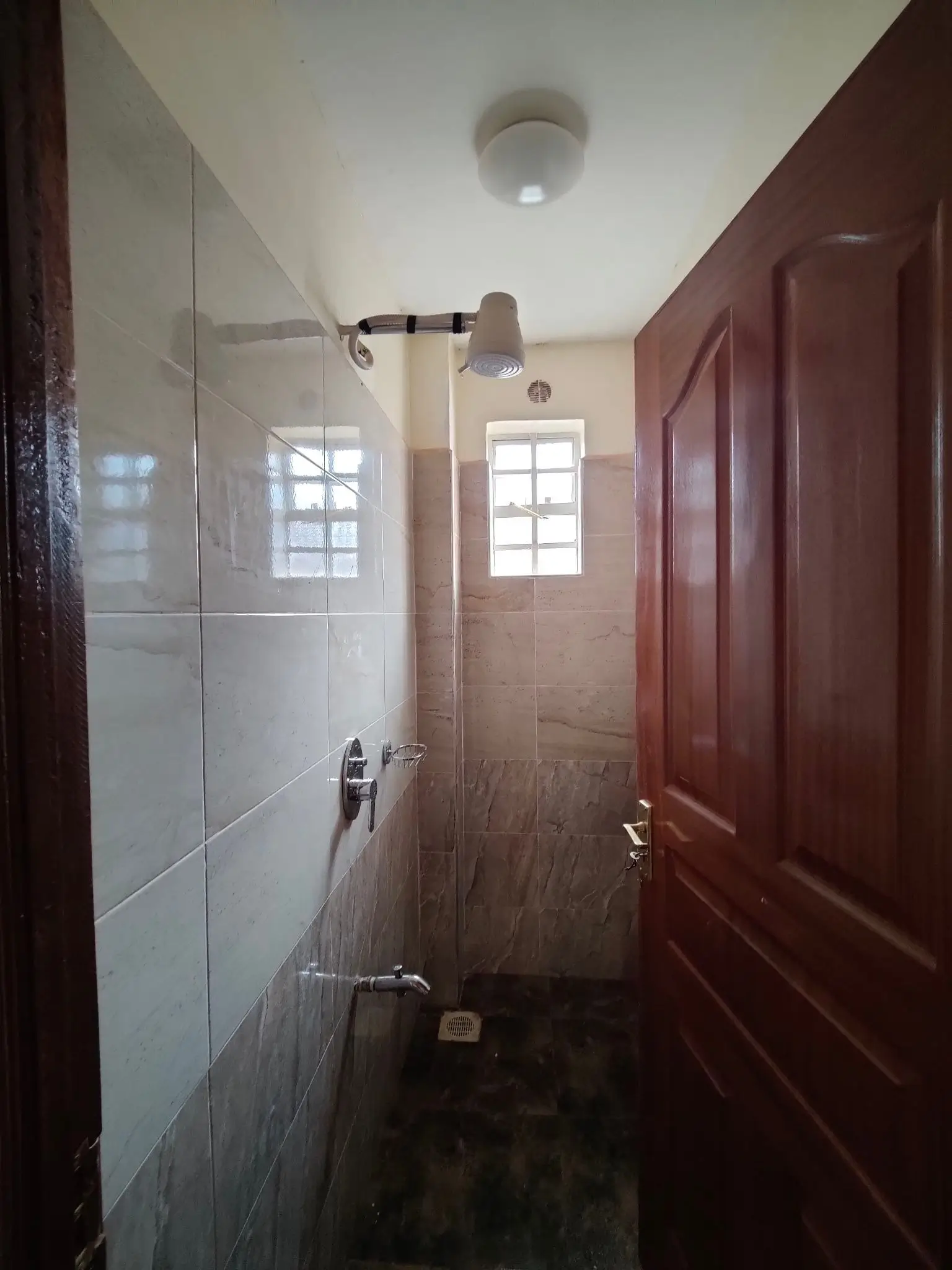 Narrow bathroom with white tiled walls and natural light