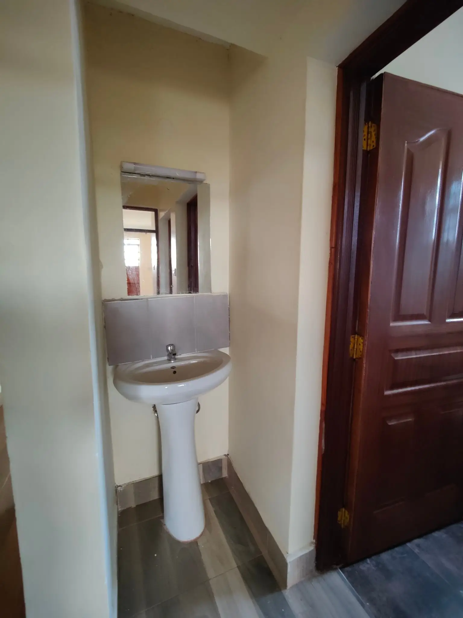 Compact bathroom with pedestal sink and mirror