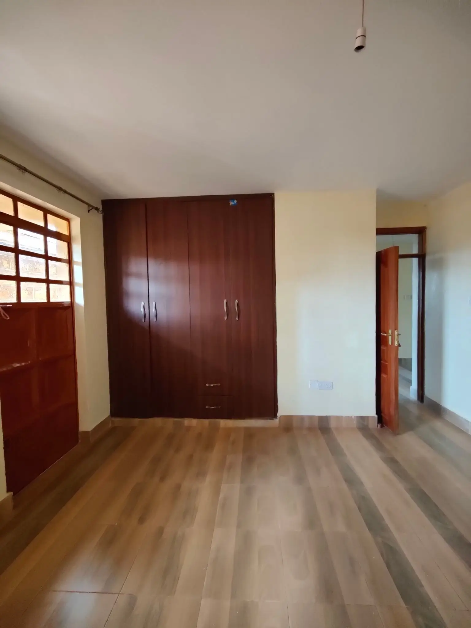 Empty bedroom with wooden flooring and built-in wardrobe