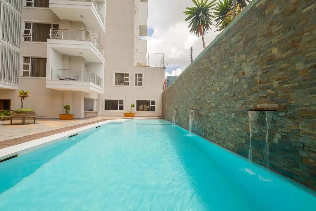 Resort-style swimming pool with slate accent wall and building views